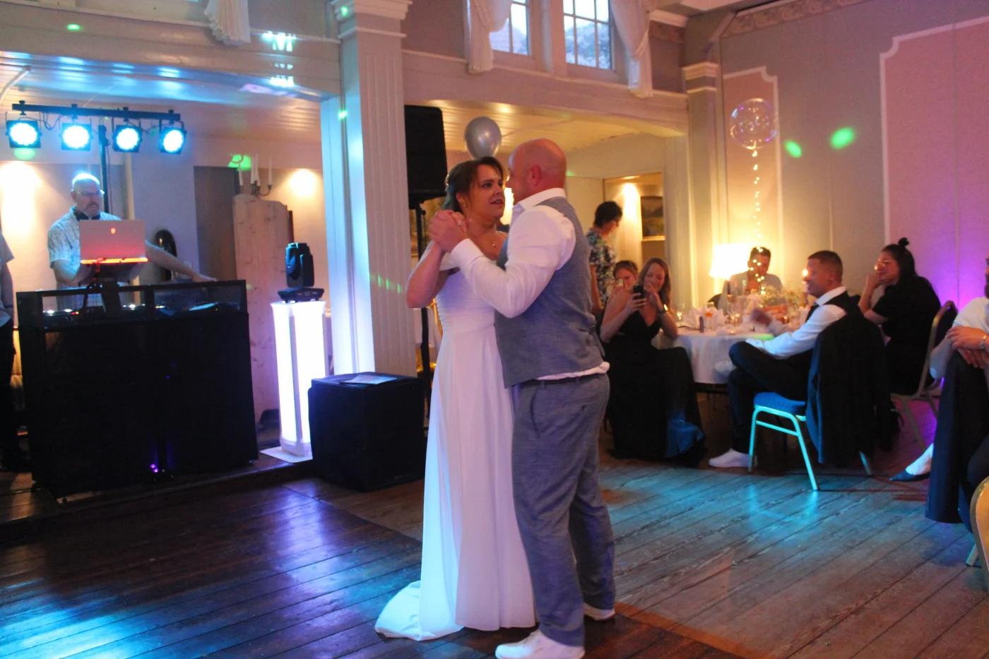 Ein Hochzeitspaar tanzt vor dem beleuchteten DJ-Setup von DMS Entertainment